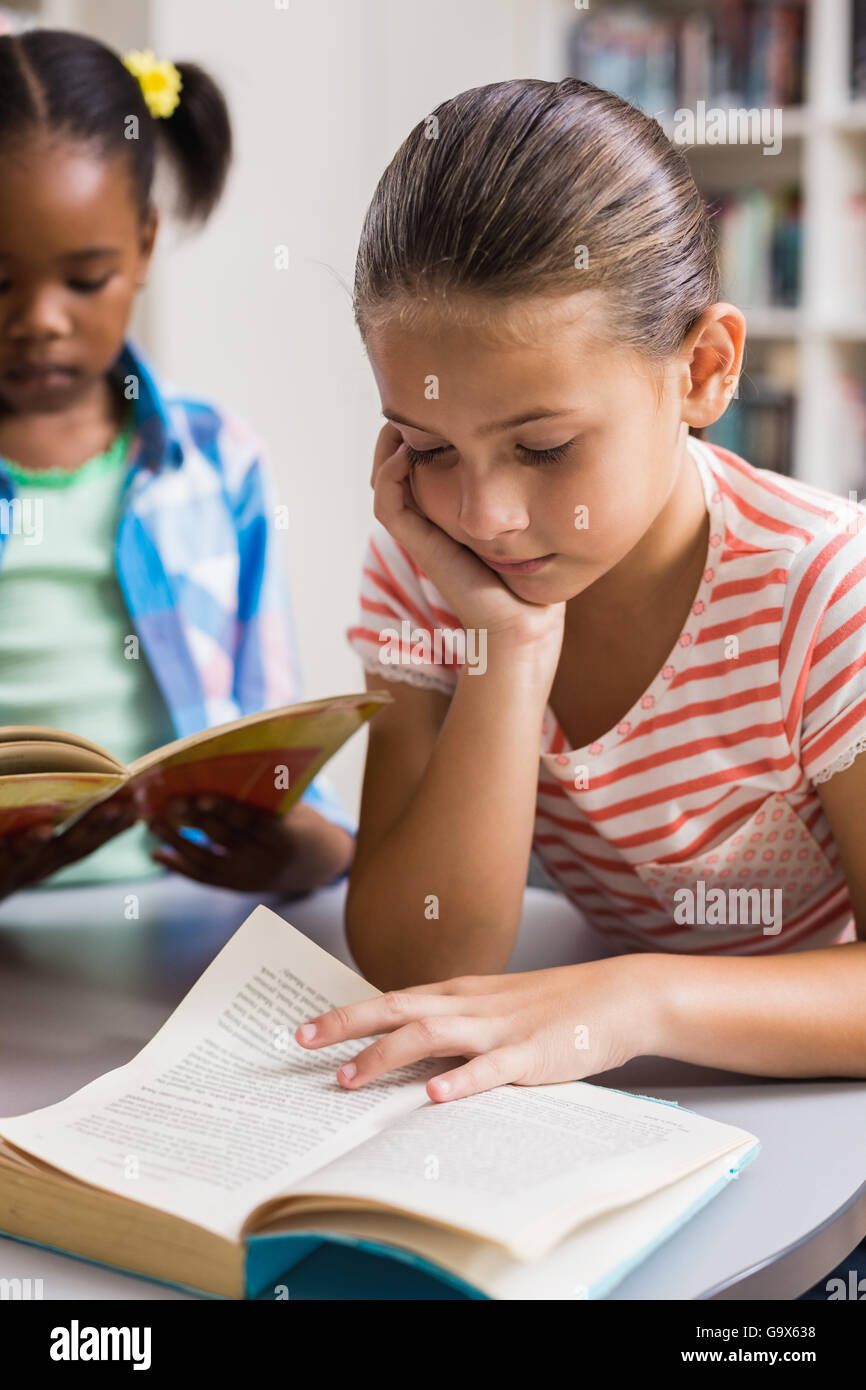 Schoolgirl reading a book in library Stock Photo - Alamy