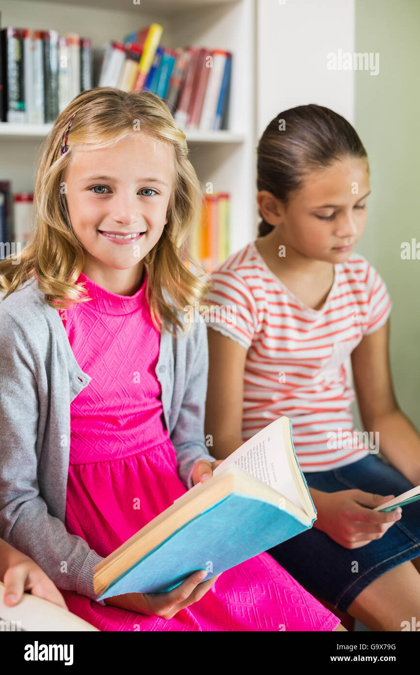 Schoolgirl reading a book in library Stock Photo - Alamy