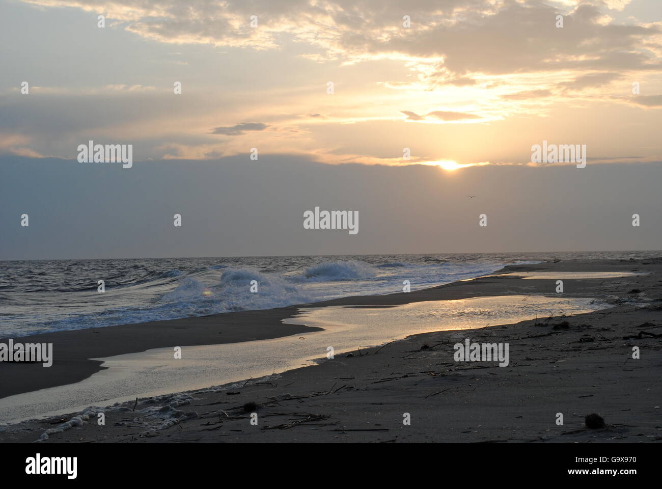 golden sunset in clouds over ocean waves on beach Stock Photo - Alamy