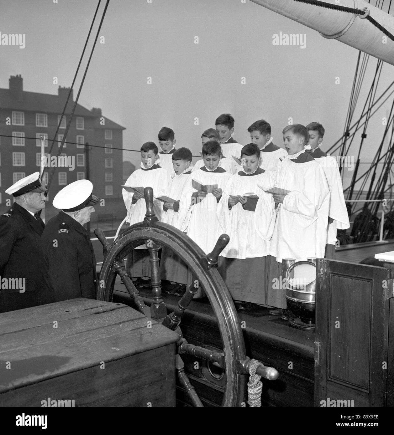 Choirboys from Vanbrugh Castle, the RAF Benevolent Fund's orphanage at Blackheath, London, blend Christmas tradition with maritime history as they sing carols on the deck of the Cutty Sark, last of Britain's great clipper ships, at Greenwich. Listening by the ship's wheel is Lieutenant-Commander H.J. West, RNR (right), Chief Officer of the Cutty Sark. Stock Photo