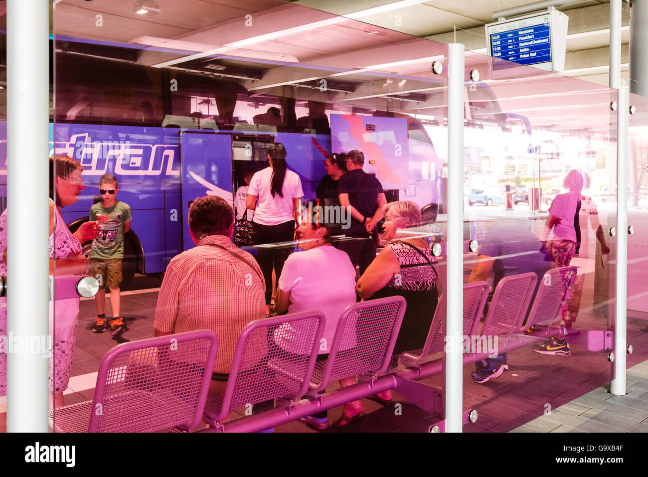 Stuttgart, Germany - June 25, 2016: People waiting for a bus as seen through modern pink glass in the new Stuttgart Central Bus Stock Photo