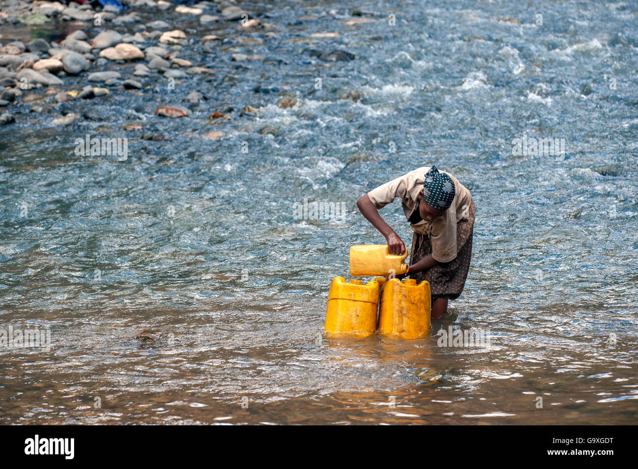 Oromo tribe girl filling her yellow water containers from the Web River (Weyib River) in Islam’s sacred valley - Sof Omar. Bale Stock Photo