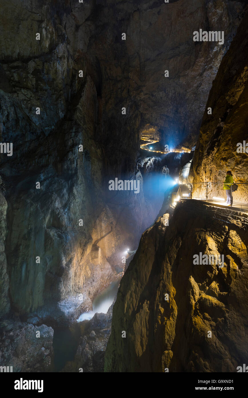 Tourist walking along illuminated footpath in Skocjan Caves, looking down into underground stream, Green Karst, Slovenia, Europe Stock Photo