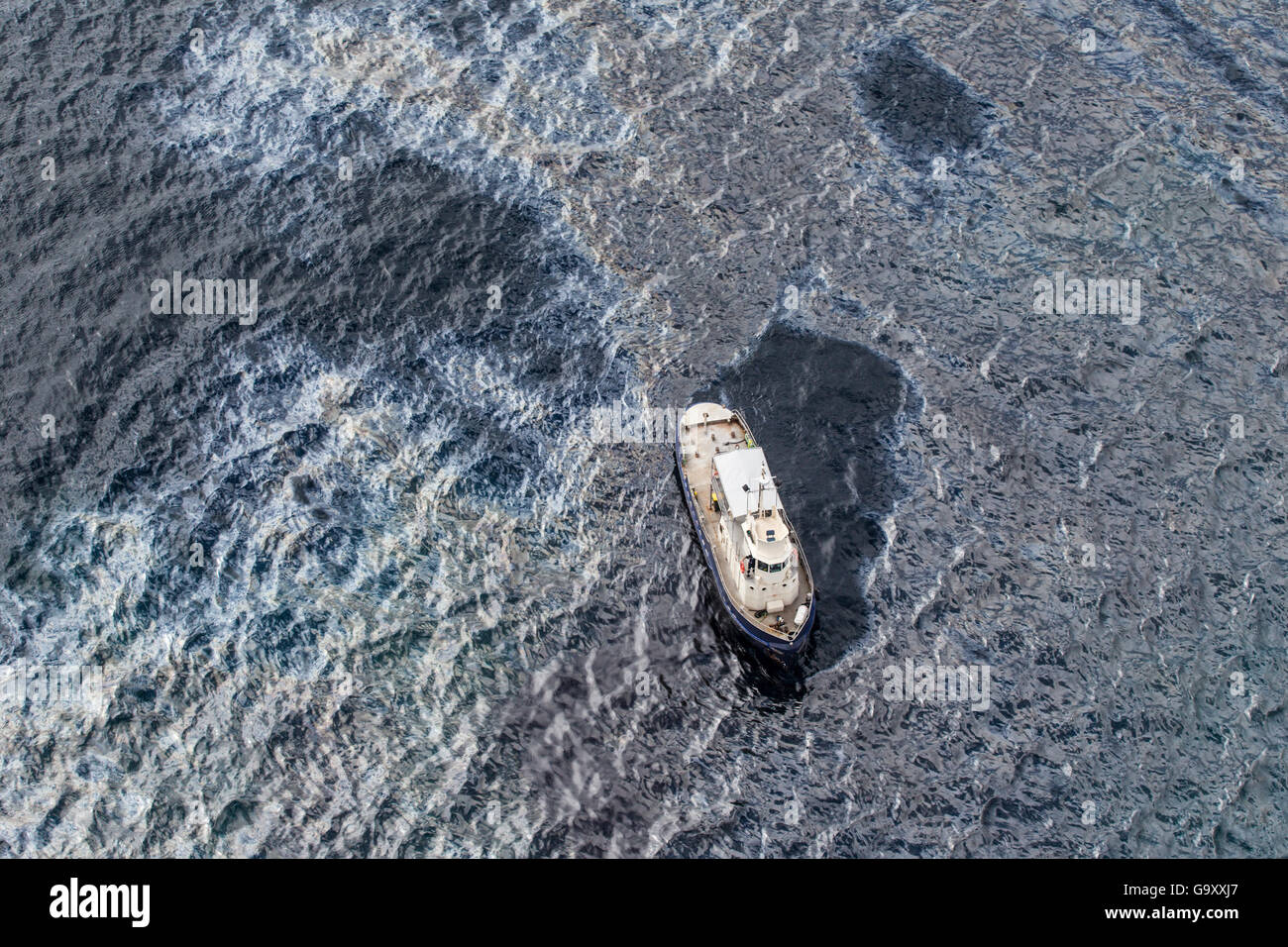 Oil slick and sheen on the sea surface around a service vessel, two days after the container ship MV Rena became grounded on Ast Stock Photo