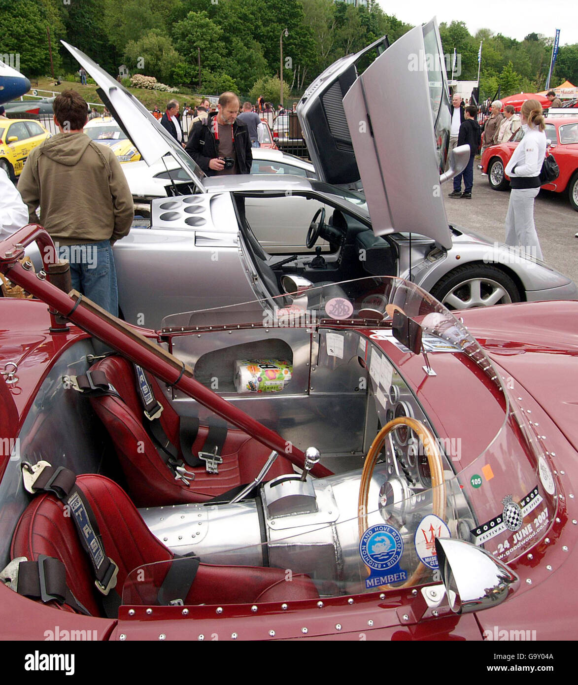 Visitors look at a Bugatti EB 110 with the cockpit of a Maserati 4000 in the foreground, which has been converted for racing, during the Brooklands Museum Italian Car Day. Stock Photo