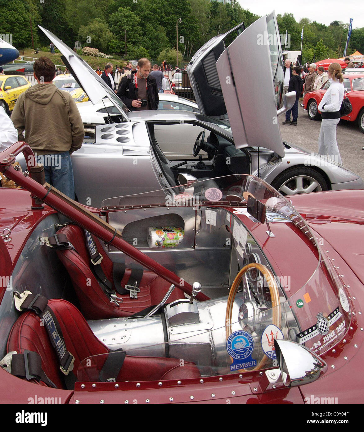 Visitors look at a Bugatti EB 110 with the cockpit of a Maserati 4000 in the foreground, which has been converted for racing, during the Brooklands Car Museum Italian Car Day. Stock Photo