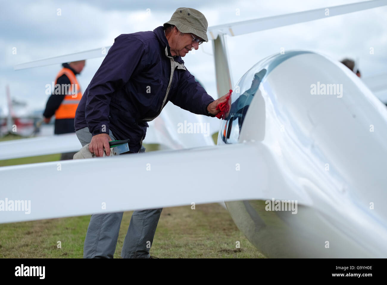 Shobdon airfield, Herefordshire, UK - July 2016 - Competitors and pilots struggle with heavy showers and rain clouds on the opening day of Competition Enterprise a week long gliding competition at Shobdon. Here a pilot wipes the rain from the cockpit canopy of his glider whilst waiting to launch. Stock Photo