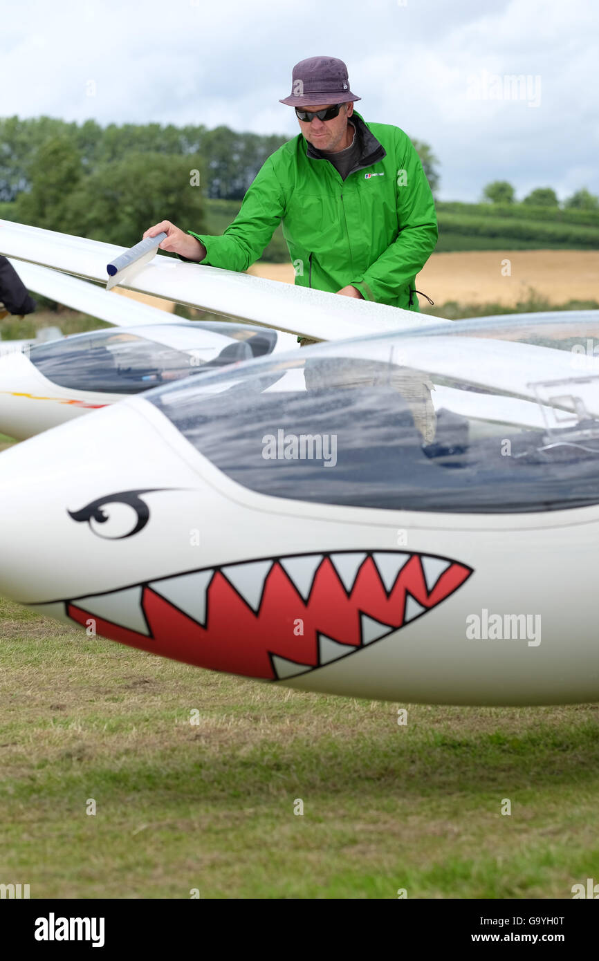 Shobdon airfield, Herefordshire, UK - Competitors and pilots struggle with heavy showers and rain clouds on the opening day of Competition Enterprise a week long gliding competition at Shobdon. Here a pilot wipes the rain from the wing of his glider whilst waiting to launch. Stock Photo