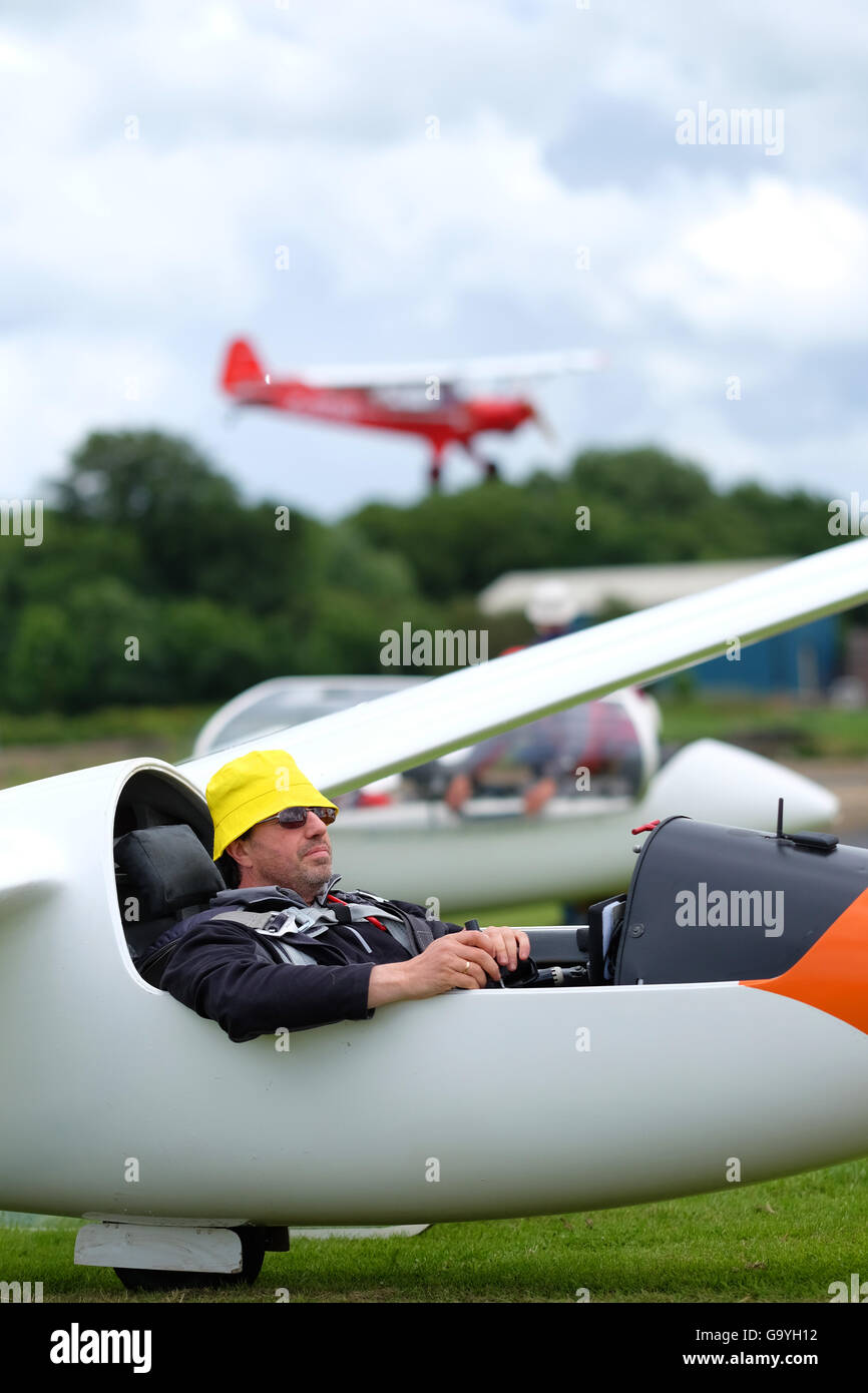Shobdon airfield, Herefordshire, UK July 2016- Opening day of Competition Enterprise a week long gliding competition at Shobdon. Here a pilot waits patiently for his turn to launch whilst a tug towing plane lands in the background. Stock Photo