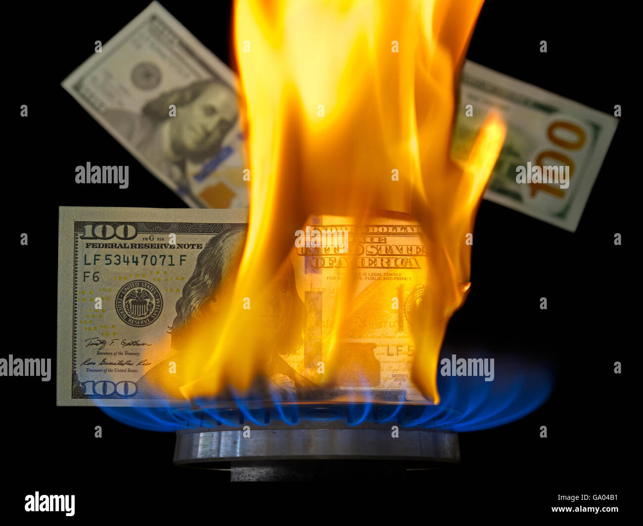 Aflame dollar bill. One hundred dollar bill on fire in gas burner flame. Gas burner burning 100 dollar bill on black background. Stock Photo