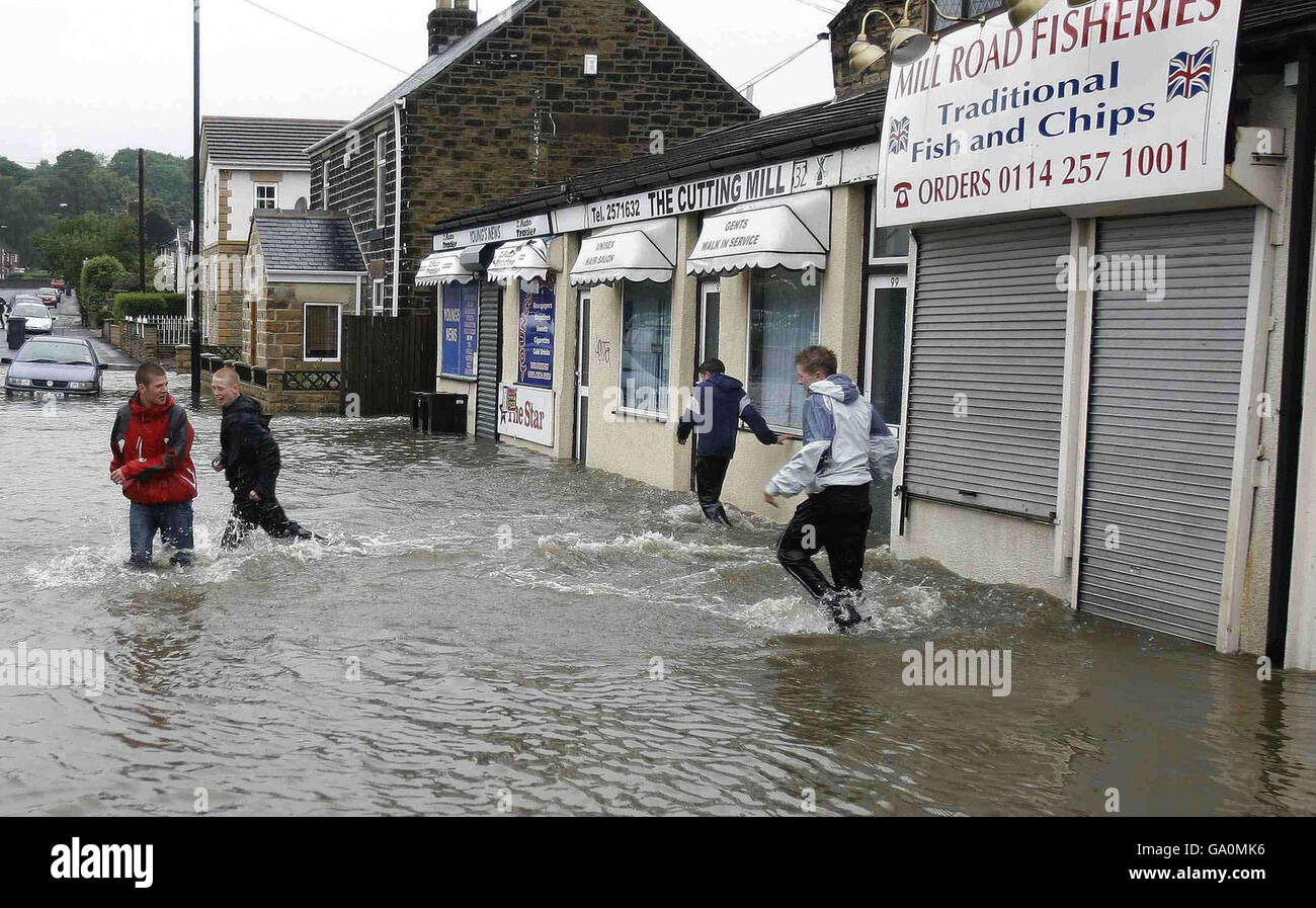 Local youths walk through flood waters in Ecclesfield, near Sheffield, following heavy rain. Stock Photo