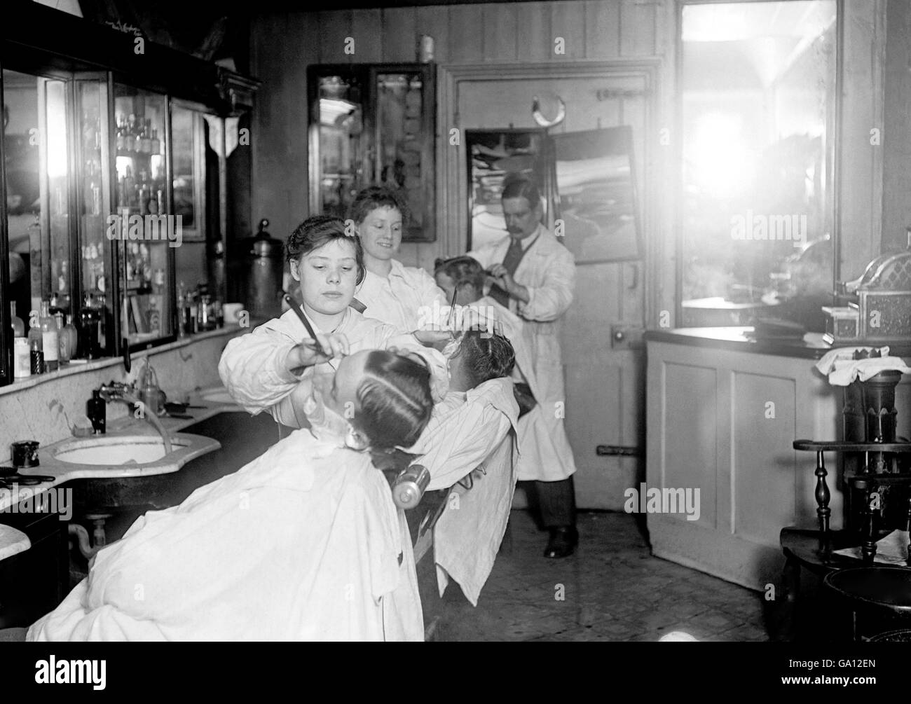 A fifteen year old girl works in a barber's shop near to Waterloo Station. Women were encouraged to take on roles traditionally reserved for men, as many of the men were away fighting in the trenches. Stock Photo