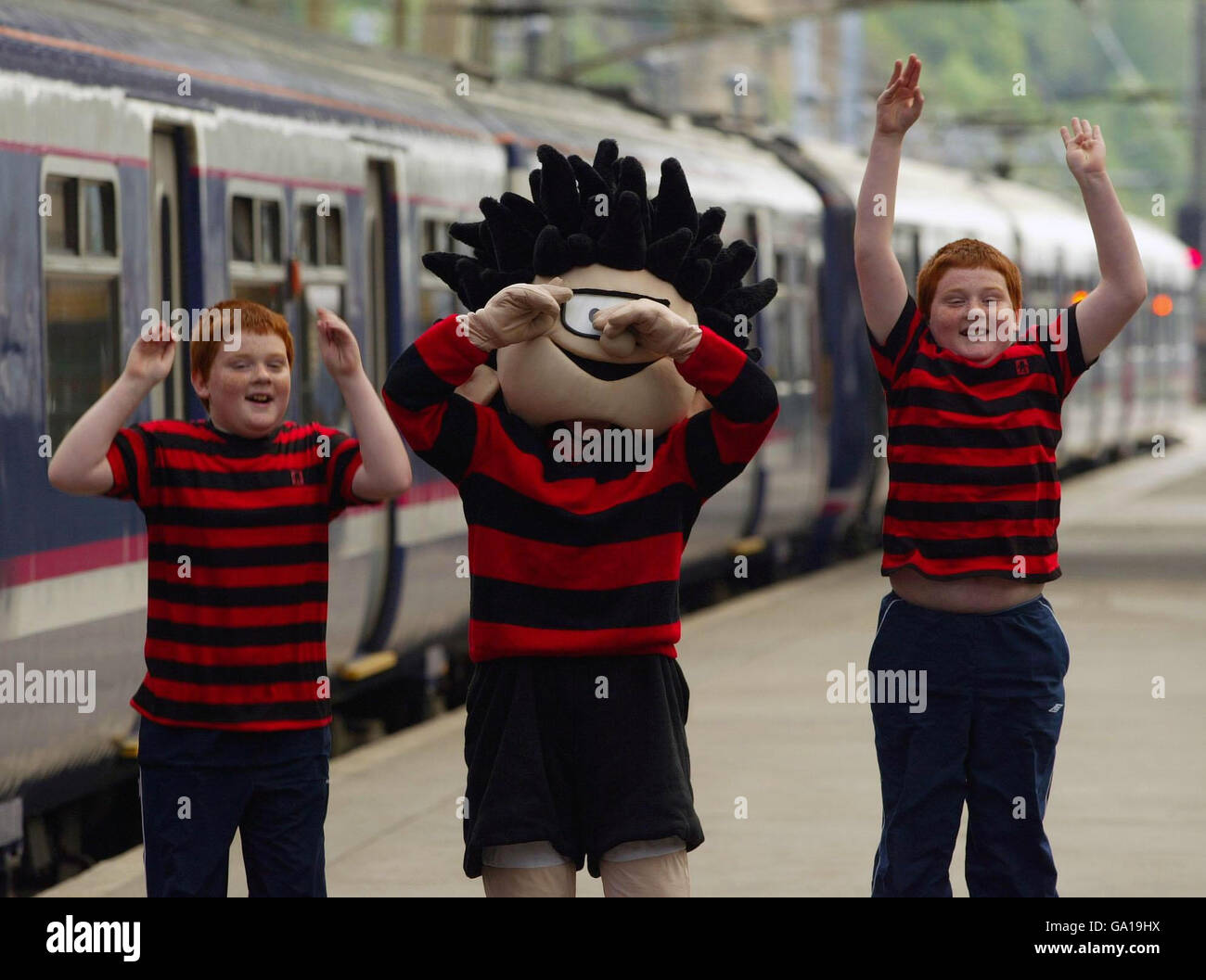 Dennis the Menace flanked by twins John (left) and Andrew Muirhead at Waverly station, Edinburgh to launch First ScotRail free travel every weekend with family Funday tickets. Stock Photo