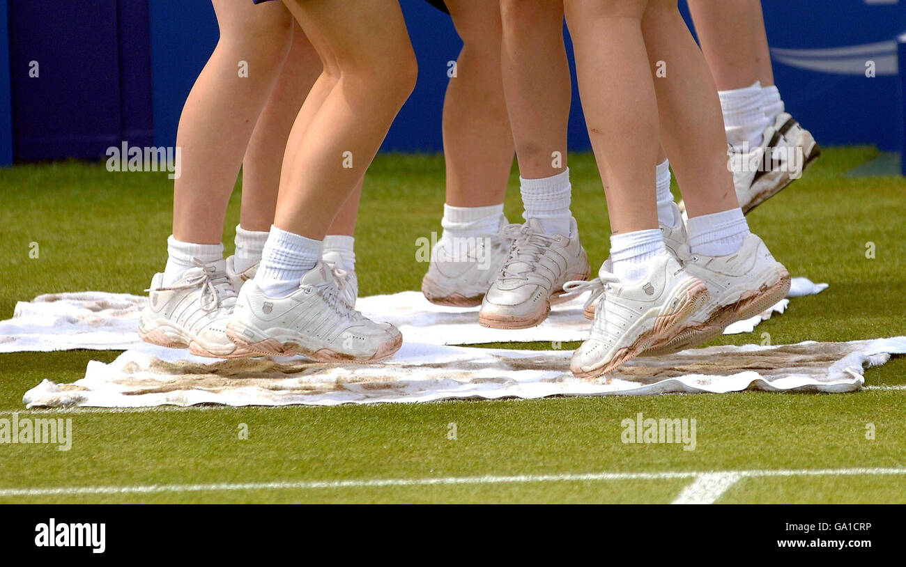 Ball girls jump on towels to dry out the centre court ahead of The DFS Classic at Edgbaston Priory Club, Birmingham. Stock Photo