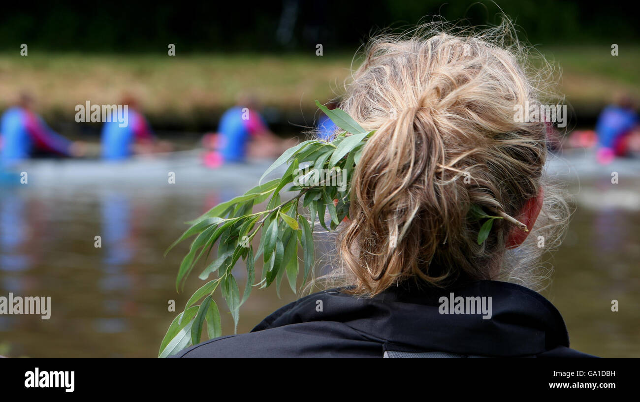 A boat crew member wearing laurel leaves watches the final Day of the Cambridge University May Bumps from the banks of the River Cam at Fen Ditton, Cambridgeshire. Stock Photo