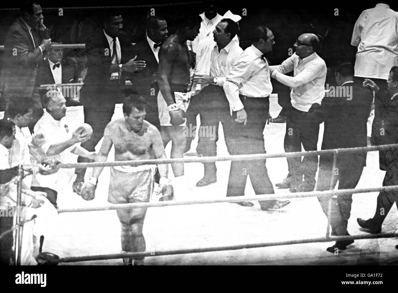 A battered and bruised Brian London (bottom l) returns to his corner for a sponging down as Muhammad Ali (c) talks to officials after his three round KO victory Stock Photo