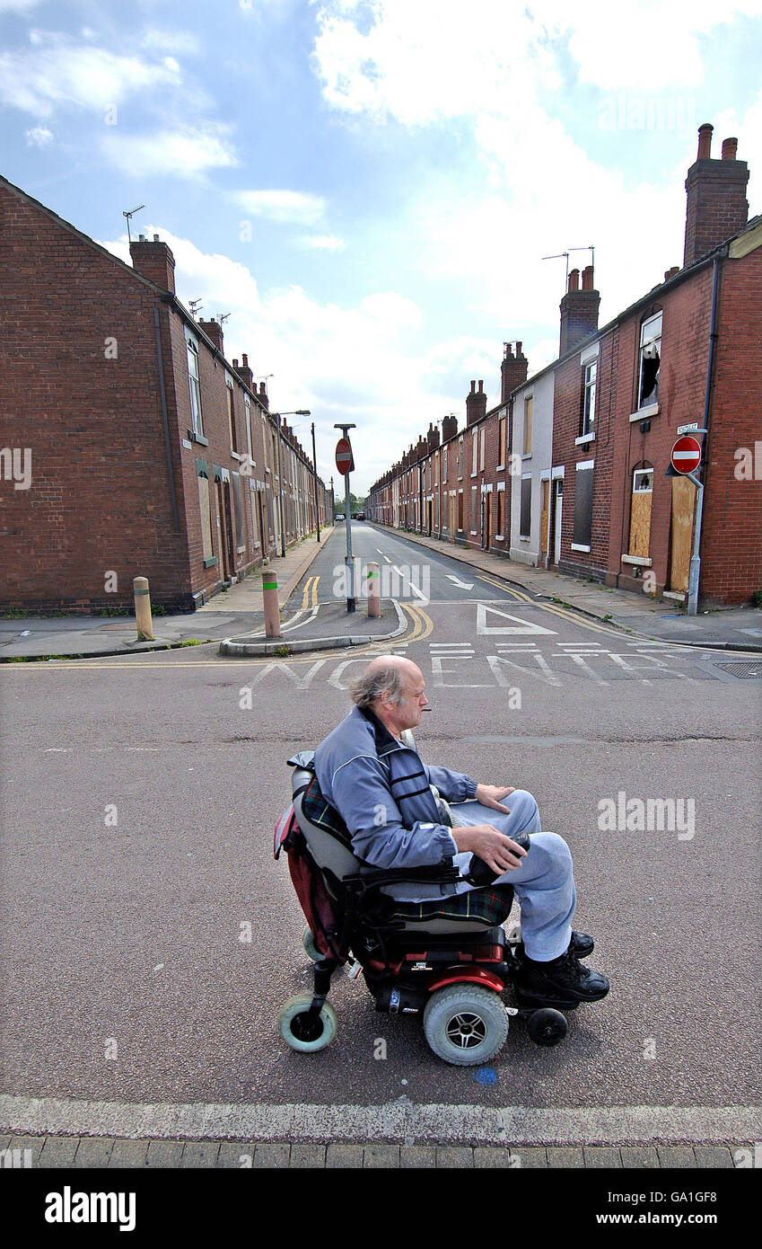 Urban decay stock. A man in a wheelchair passes a terraced street, boarded up and nearly all empty, in Doncaster. Stock Photo