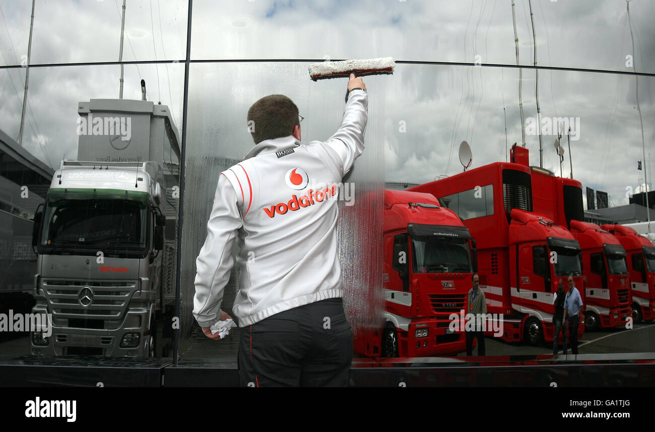 McLaren staff cleans the window of the Vodafone McLaren Mercedes Motorhome in the Silverstone