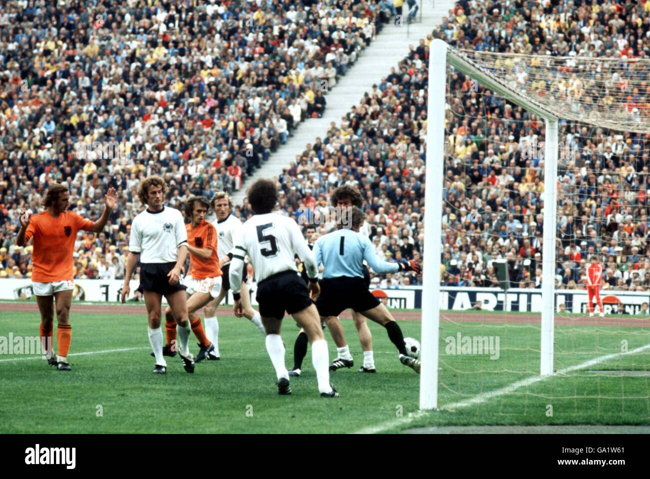 West Germany goalkeeper Sepp Maier (r) almost drops the ball into his own net, watched by teammates Paul Breitner (r, hidden) and Franz Beckenbauer (third r), as Holland's Rob Rensenbrink (c) waits to pounce Stock Photo