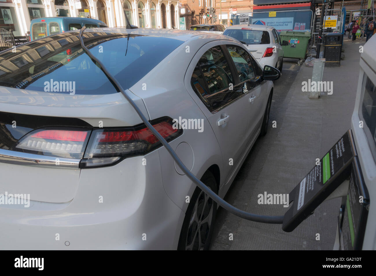 Electric vehicle parked at city centre street charging station, Glasgow
