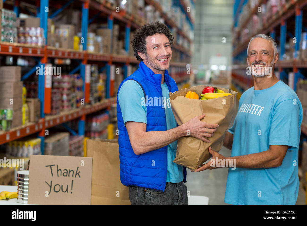 Happy volunteers holding a grocery bag and looking the camera Stock