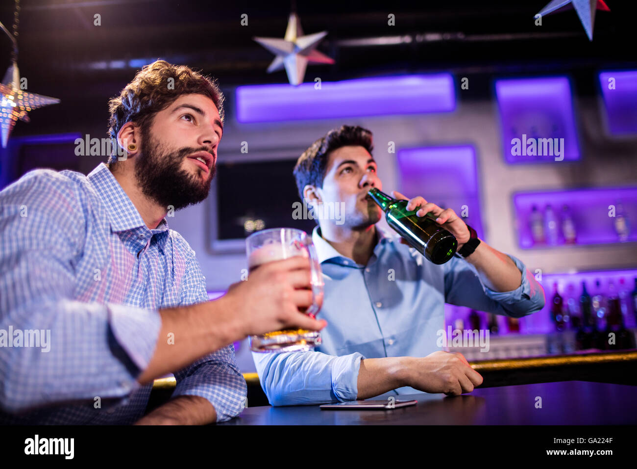 Friends sitting at bar counter and having beer Stock Photo