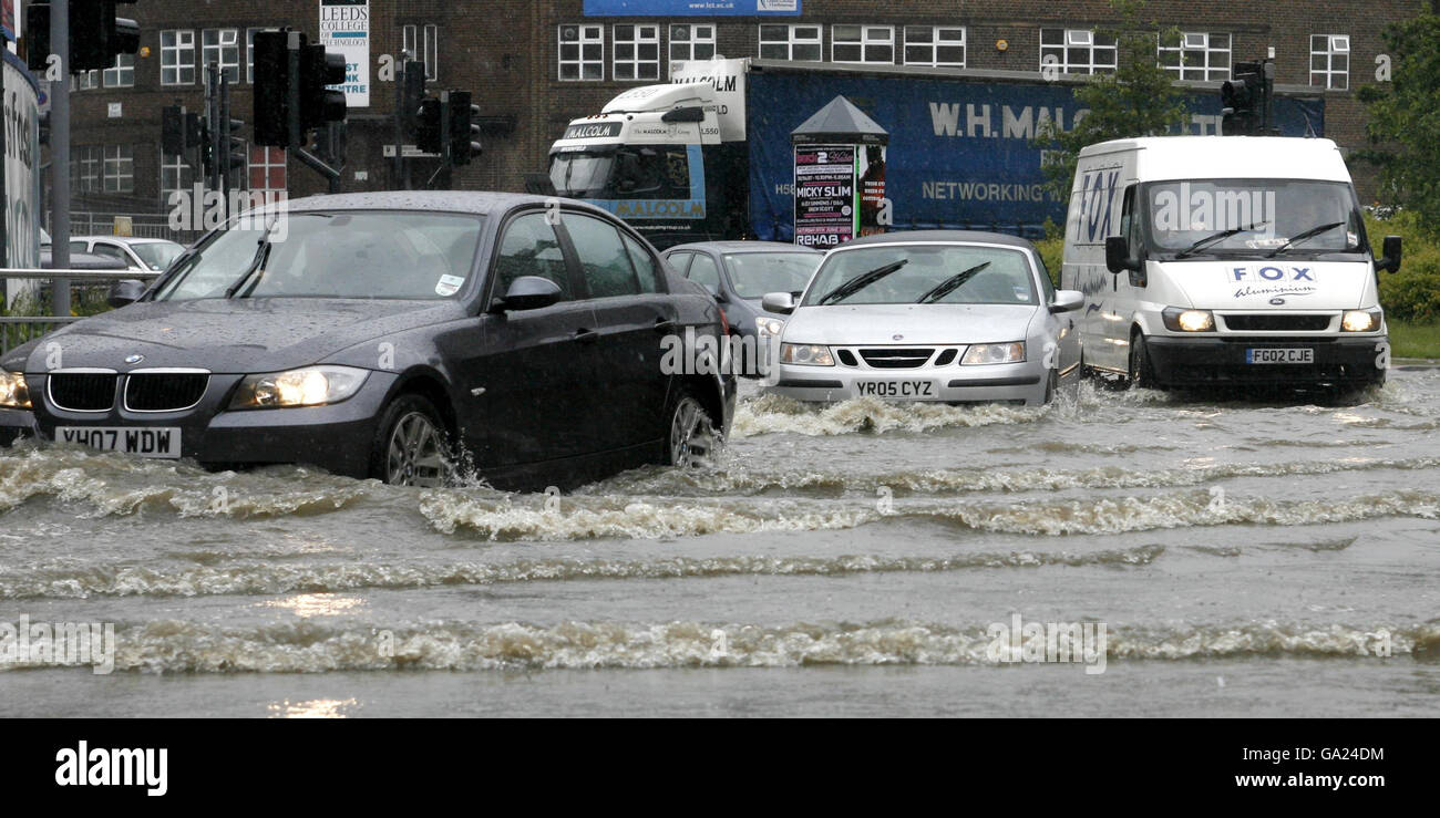 Motorists drive through flood waters after the banks of the River Aire ...
