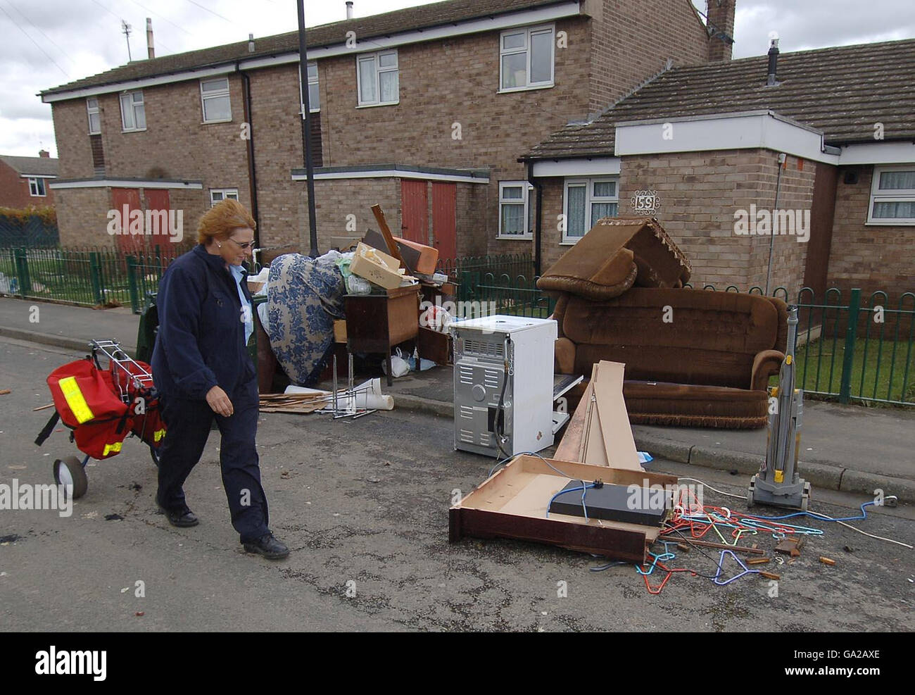 Flooding hits Britain. A postal worker walks past ruined possessions in Toll Bar, near Doncaster, which was hit by heavy flooding. Stock Photo