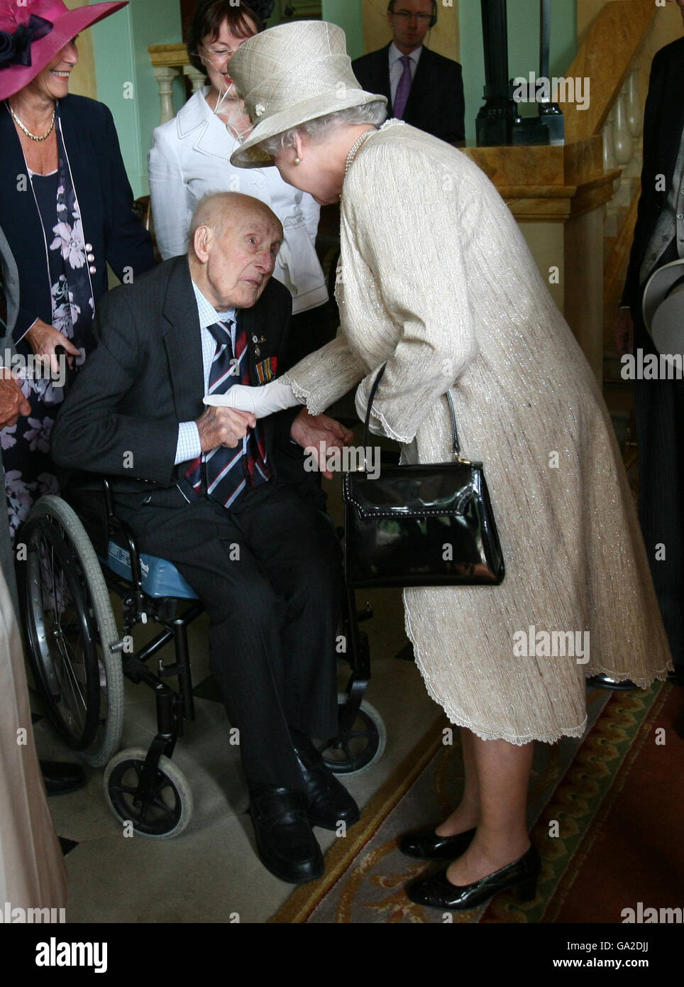 Britain's Queen Elizabeth II (right) meets the oldest surviving soldier from the First World War, 111 year old Henry Allingham (centre), at the Buckingham Palace Garden Party in London. Stock Photo