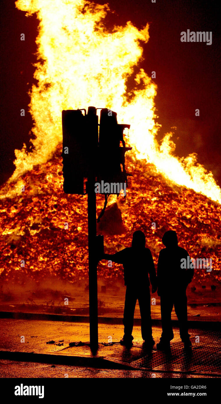Two youths watch a bonfire on the Shankil Road in Belfast. Bonfires are lit on the night before the Twelfth of July as part of the loyalist celebration. Tens of thousands of Orangemen and supporters are expected to attend Northern Ireland's Twelfth of July parades. Stock Photo