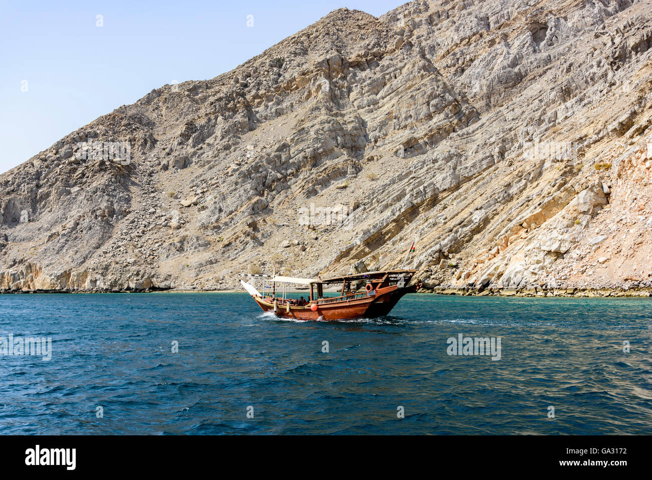 Traditional Arabic Dhow sailing with tourists in th wild fjord of Musandam peninsula, Sultanate of Oman Stock Photo