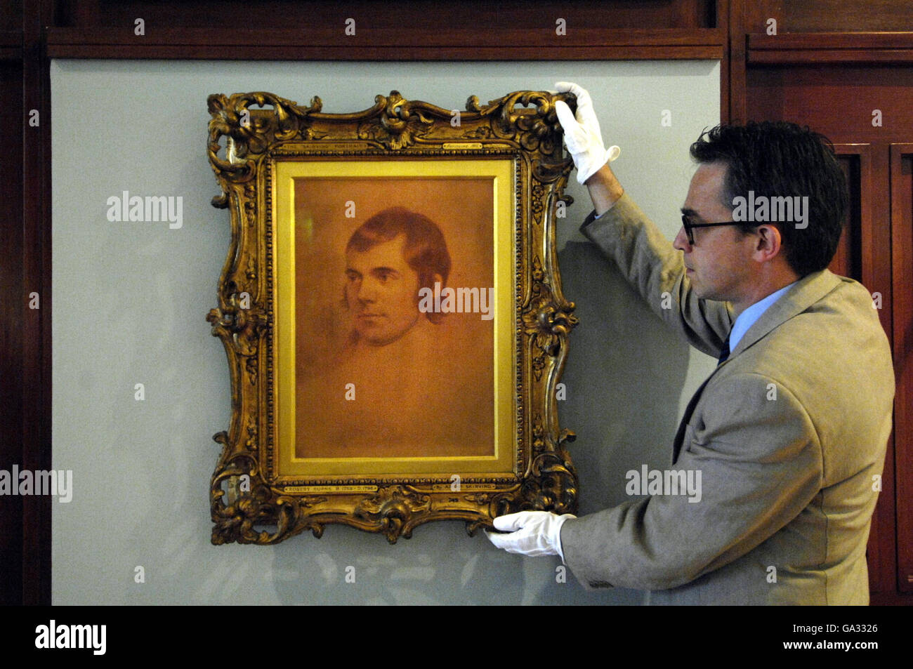 Dr Stephen Lloyd, Senior Curator of the National Galleries of Scotland, helps hang a picture of Robert Burns by Archibald Skirving, part of the Painting in Crayons: Pastel Portraits exhibition on show at Scottish National Portrait Gallery in Edinburgh, form 21 July to 30 September 2007. Stock Photo