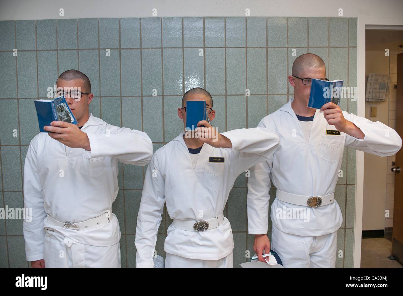 U.S Naval Academy incoming freshmen known as Plebes stand against a wall in Bancroft Hall reading their Reef Points during Induction Day June 30, 2016 in Annapolis, MD. Induction Day begins when the incoming plebes are issued uniforms, given medical examinations, complete registration, receive hair cuts and learn to salute. Stock Photo