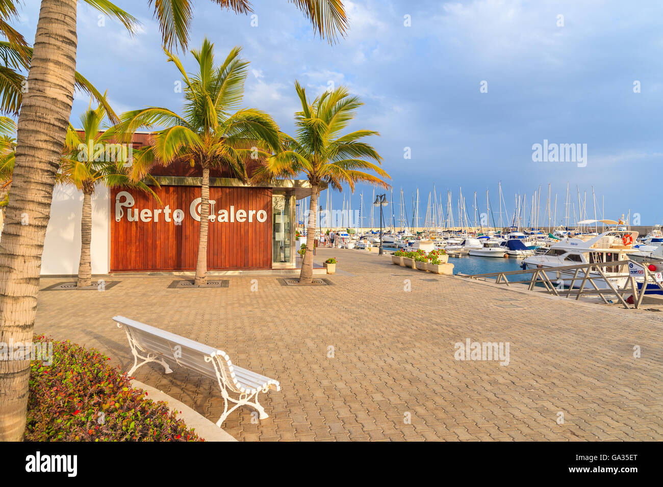 PUERTO CALERO MARINA, LANZAROTE ISLAND - JAN 12, 2015: bench and palm trees in Puerto Calero port built in Caribbean style. This is modern yacht marina which is visted by many tourists. Stock Photo