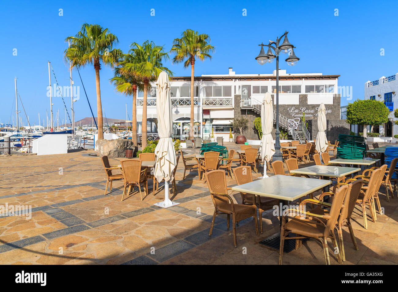 MARINA RUBICON, LANZAROTE ISLAND - JAN 11, 2015: restaurant tables in Rubicon port, Playa Blanca town. Canary Islands are popular holiday destination due to sunny tropical climate. Stock Photo