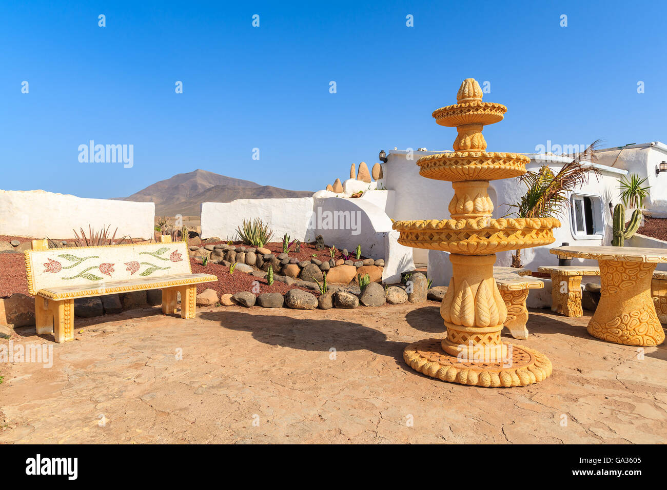 Bench and water fountain sculpture near Papagayo beach in mountain landscape of Lanzarote island, Spain Stock Photo