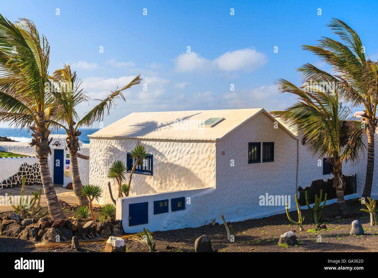 EL GOLFO BEACH, LANZAROTE ISLAND - JAN 15, 2015: Typical white house and palm tree in El Golfo village on coast of Lanzarote island, Spain. Canary Islands are popular holiday destination. Stock Photo