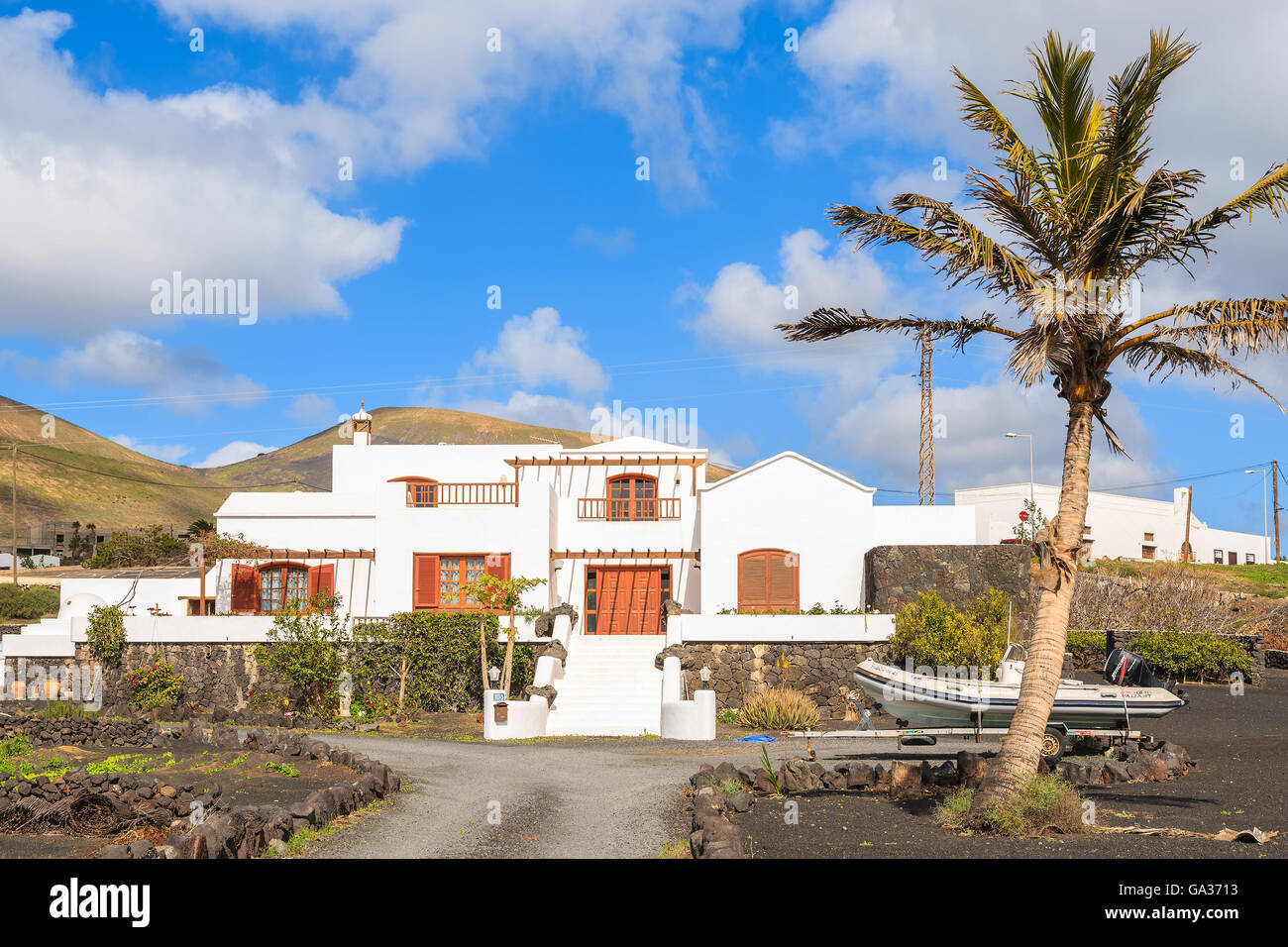 LANZAROTE ISLAND, SPAIN - JAN 17, 2015: typical Canarian house in tropical landscape of Lanzarote island, Spain. Many Europeans buy properties on Canary Islands due to sunny and warm climate. Stock Photo