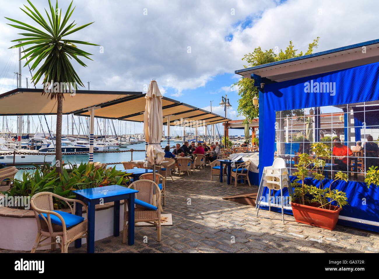 MARINA RUBICON, LANZAROTE ISLAND - JAN 17, 2015: restaurant in port with people dining in Rubicon yacht port. Lanzarote is most northern island in Canary Islands archipelago. Stock Photo