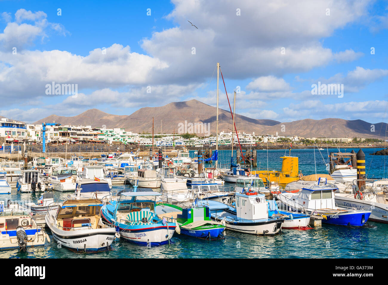 PLAYA BLANCA PORT, LANZAROTE ISLAND - JAN 17, 2015: colourful fishing boats in Playa Blanca harbour on sunny day. Lanzarote is very popular tourist destination among Canary Islands archipelago. Stock Photo