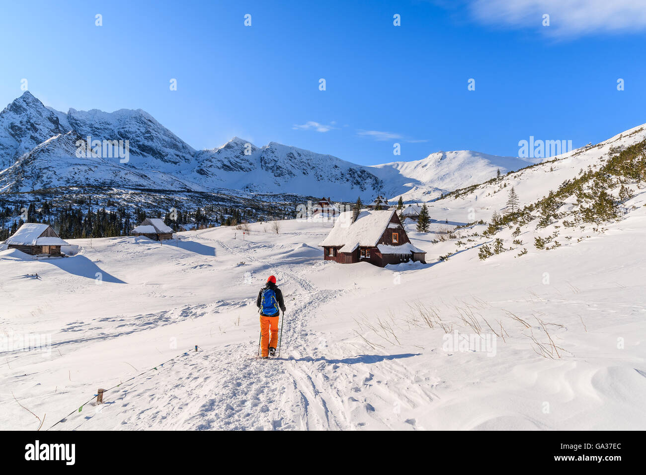 Young woman backpacker tourist walking to mountain huts in winter landscape of Gasienicowa valley, Tatra Mountains, Poland Stock Photo