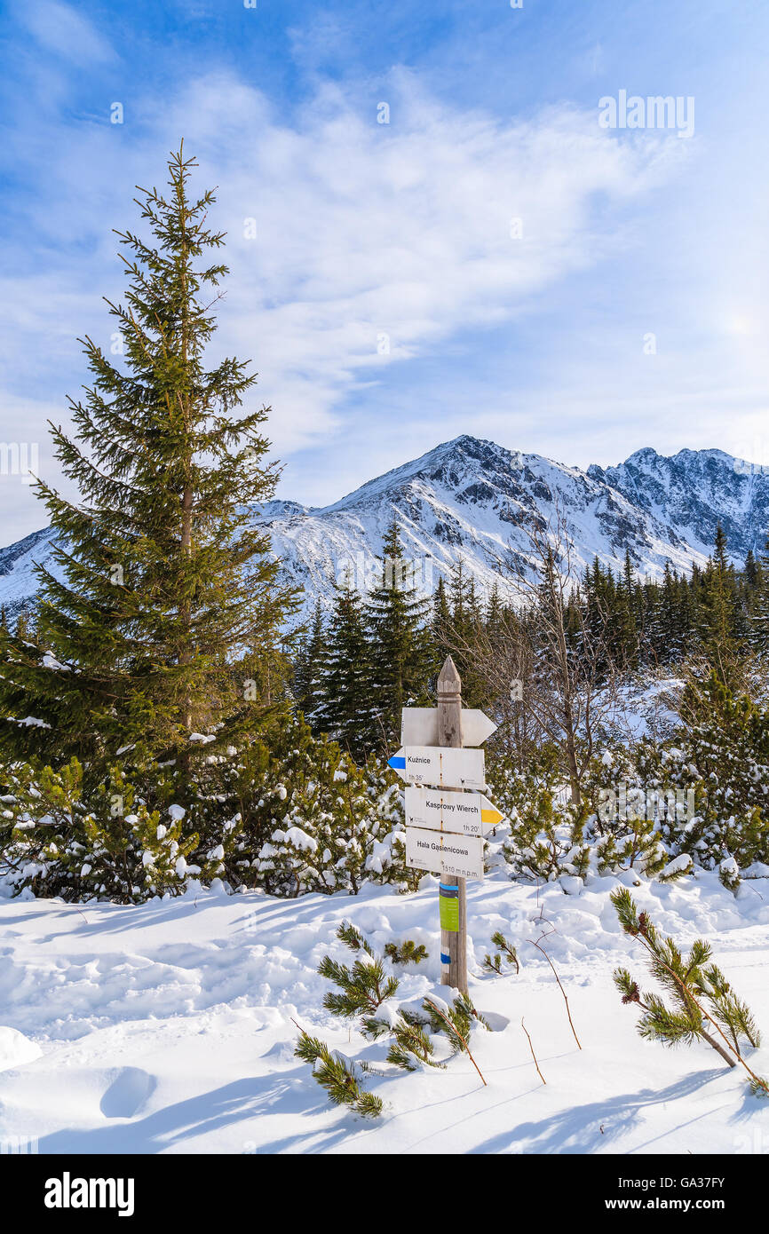 Mountain trail sign in Gasienicowa valley with peaks covered with snow in distance, Tatra Mountains, Poland Stock Photo