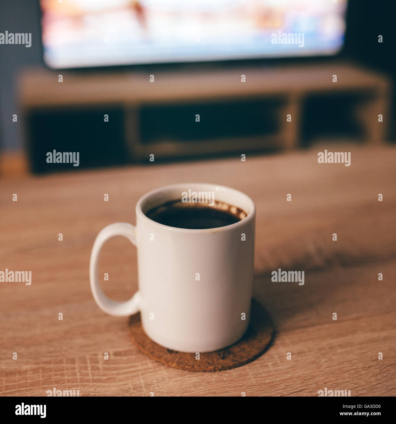 Morning coffee in white cup, shallow dof, television in background, selective focus Stock Photo
