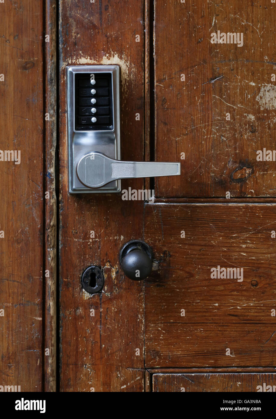 Simple door handle electronic lock with numeric buttons on old wooden door Stock Photo