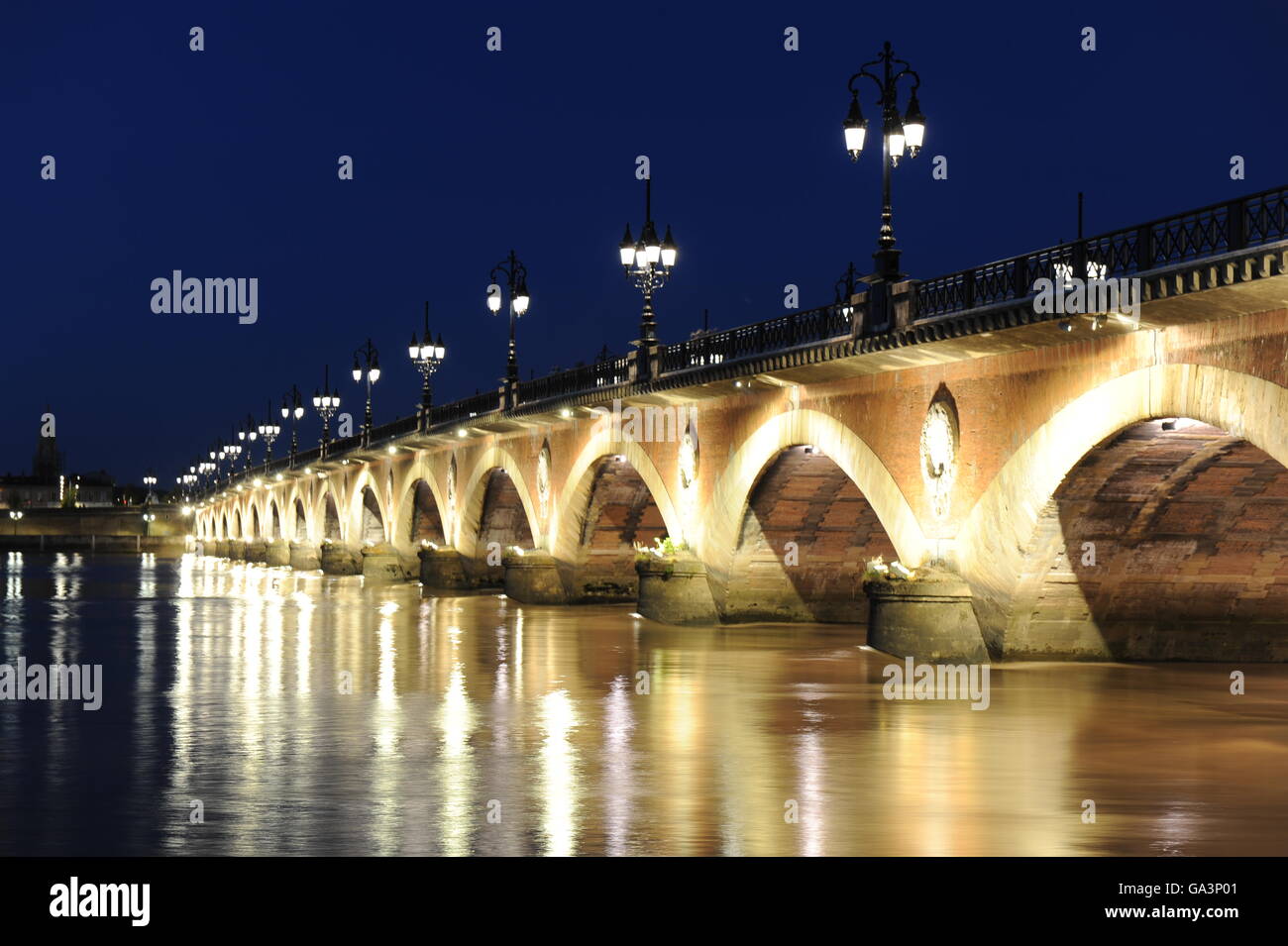 The 'Pont de Pierre' (Stone Bridge) over the Garonne river, seen in a July night light, Bordeaux. Stock Photo