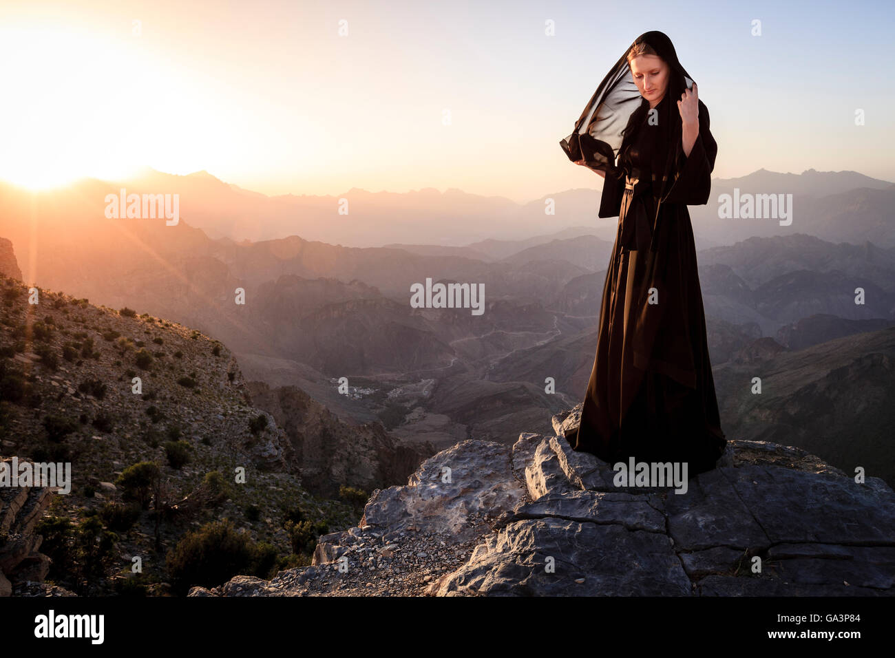 Lone woman in abaya in Al Hajar Mountains of Oman at sunset Stock Photo