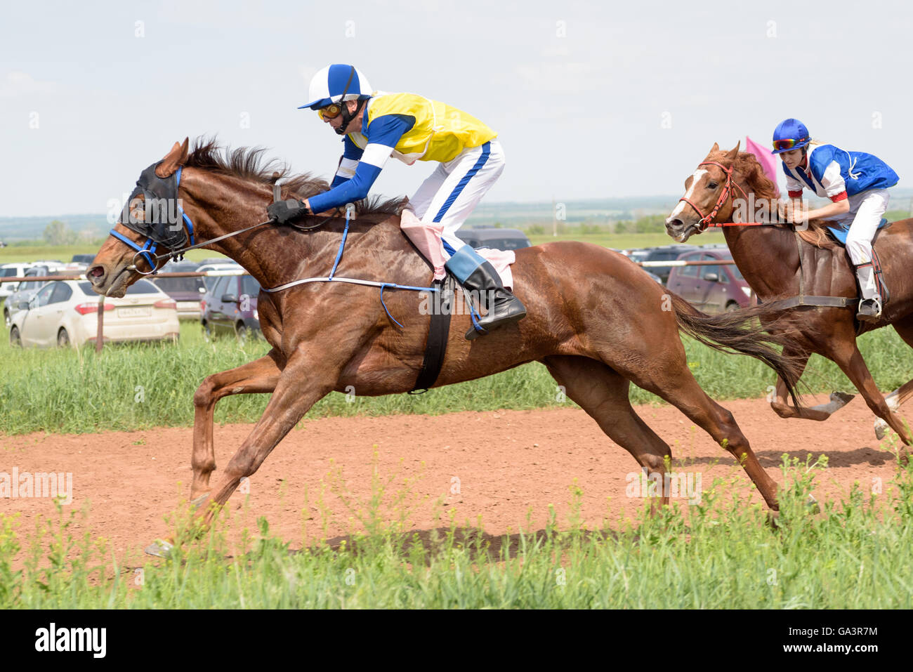 Galloping horses and their riders at a horse racing event in Summer Stock Photo