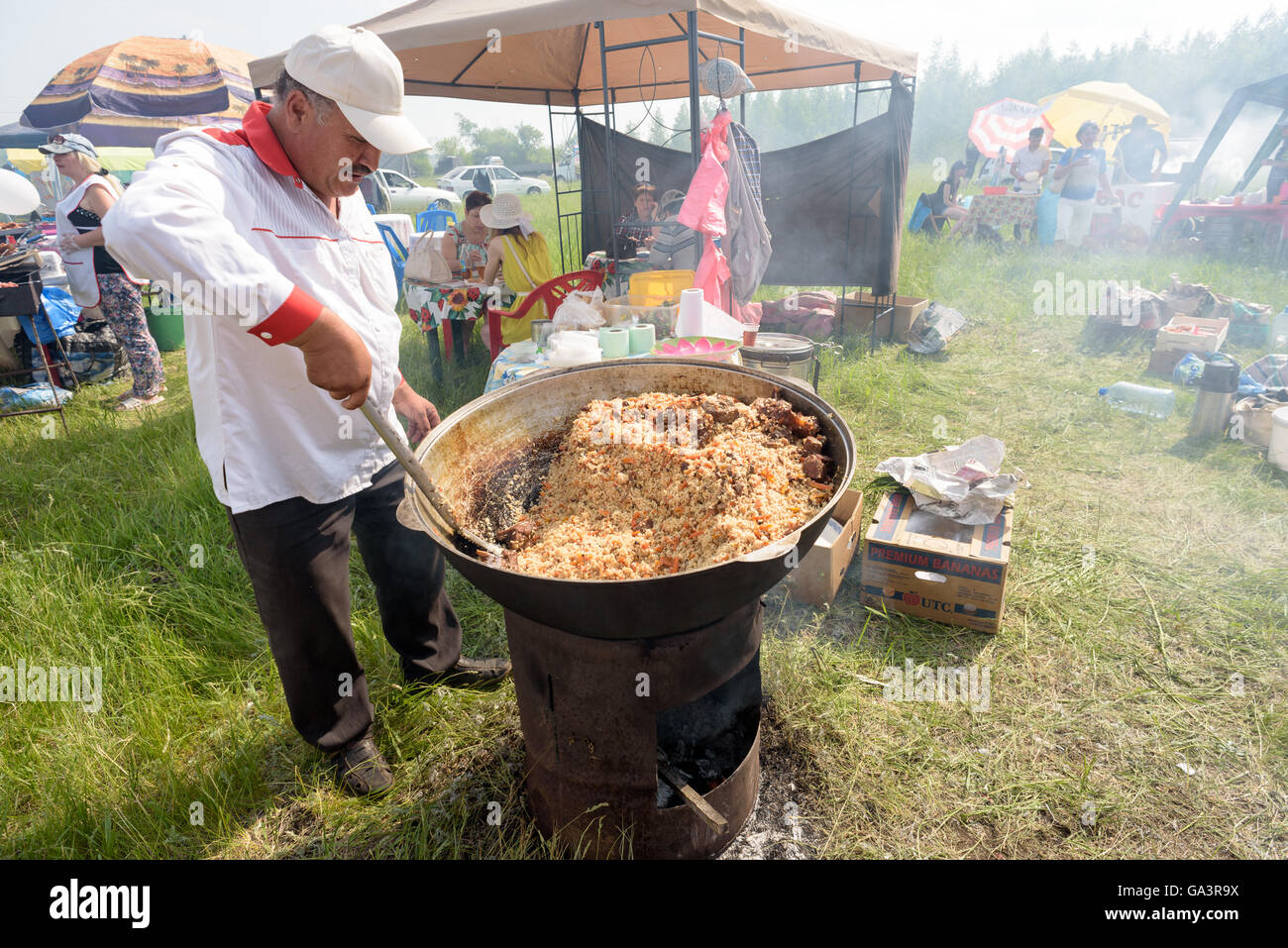 Russian man cooks a huge bowl of Plov at a local fair in Russia Stock