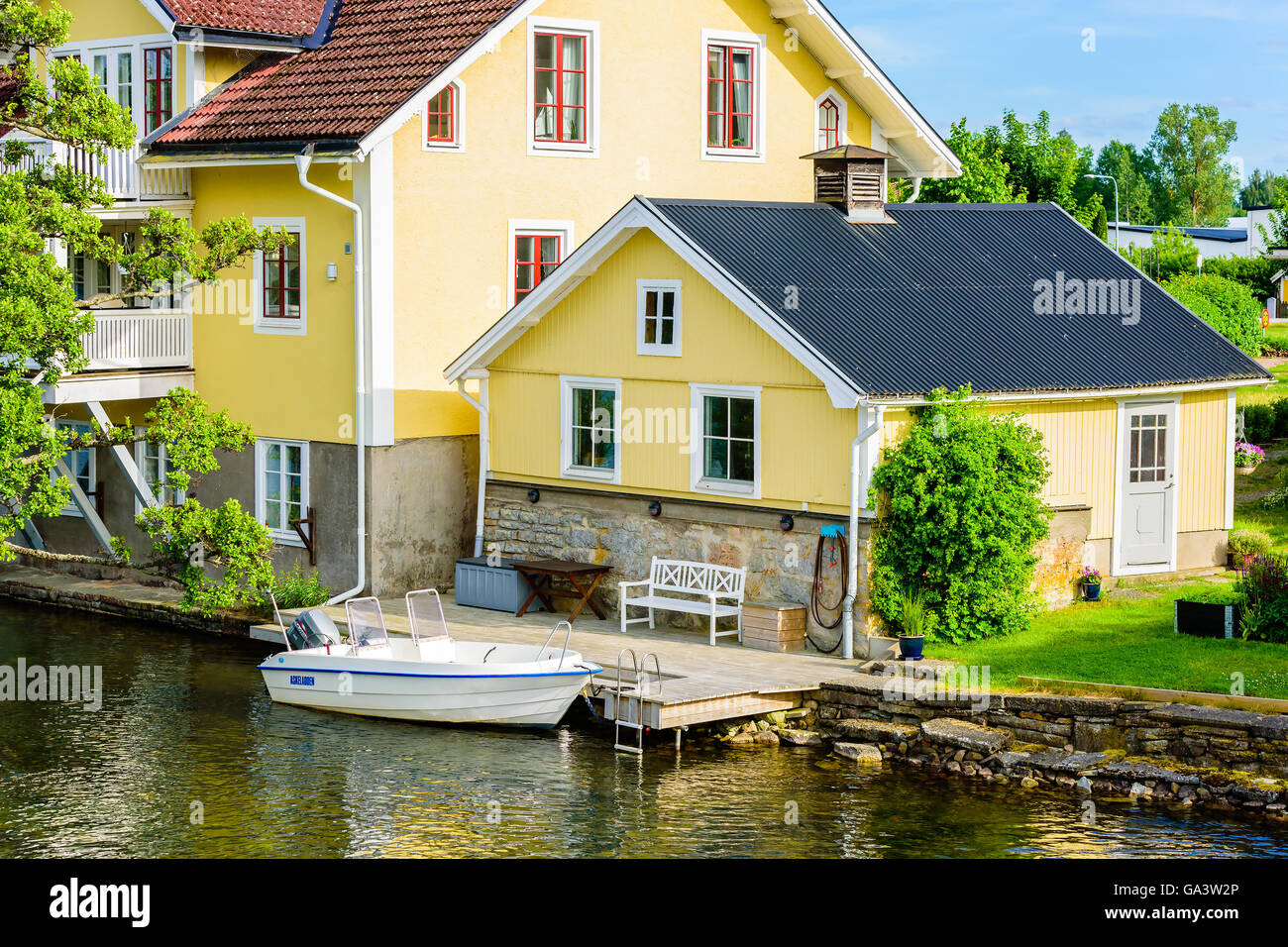 Borensberg, Sweden - June 20, 2016: Smaller house next to larger house. Jetty and a boat moored in front of the smaller house. B Stock Photo