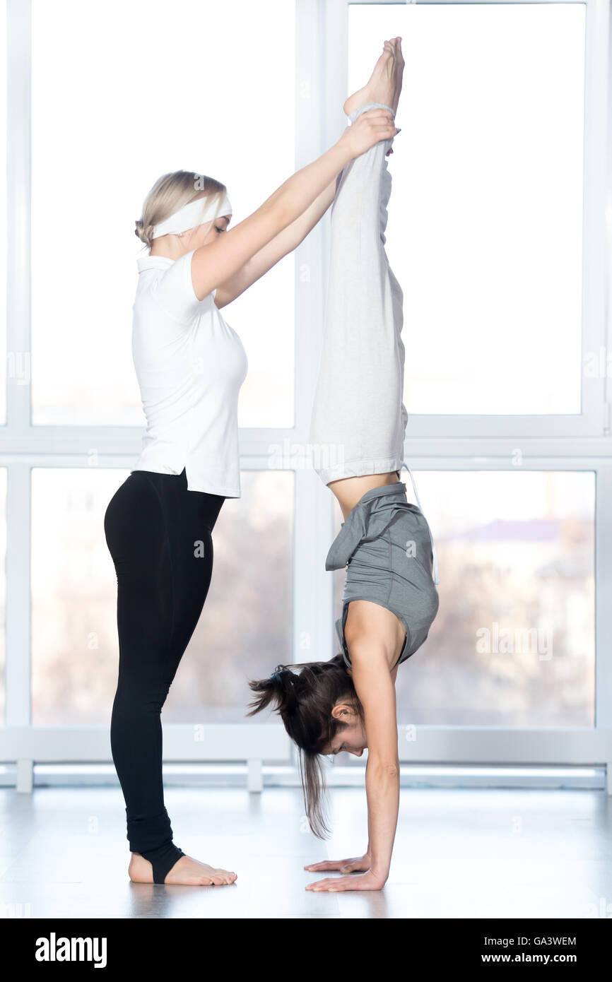 Two young women doing yoga handstand pose. Adho Mukha Vrksasana